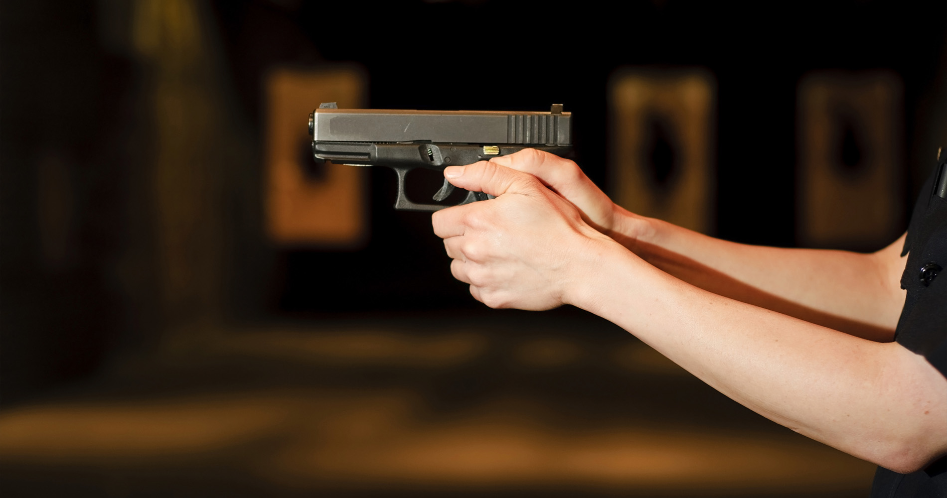 a female police officer pointing her gun at in a firing range.